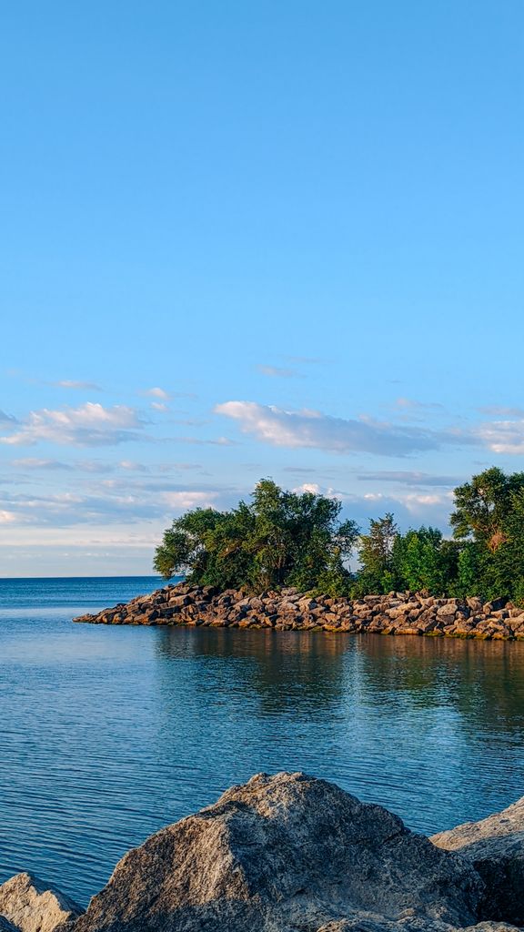 Serene coastal landscape featuring rocky shoreline and tranquil sea under a clear blue sky.
point pelee national park.