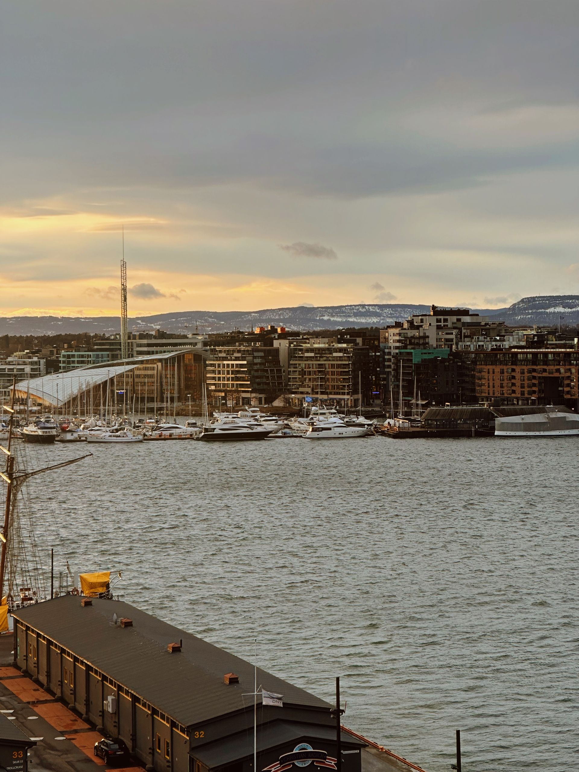 Captivating view of Oslo Harbor with city skyline and yachts at sunset.