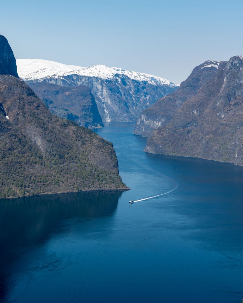 Explore the stunning fjords of Aurlandsvangen, Norway with snow-capped mountains and serene waters.
