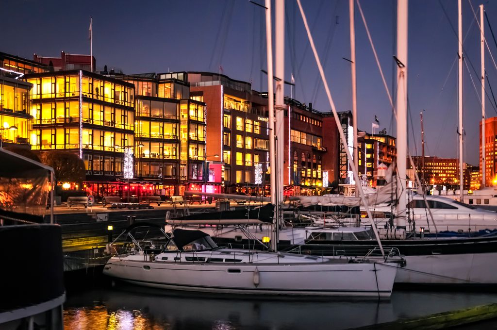 Vibrant harbor with yachts and glowing buildings at night, perfect for travel themes.