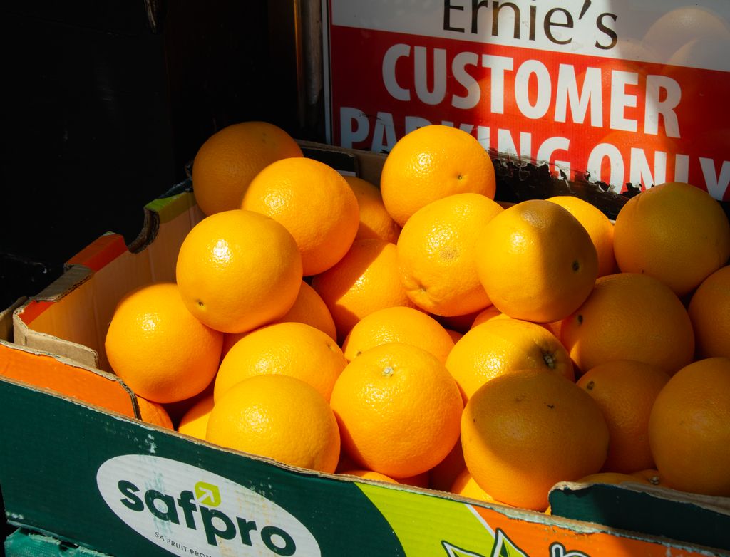 Vibrant oranges stacked in a box at a local grocery in Galway, Ireland, capturing the freshness of produce.