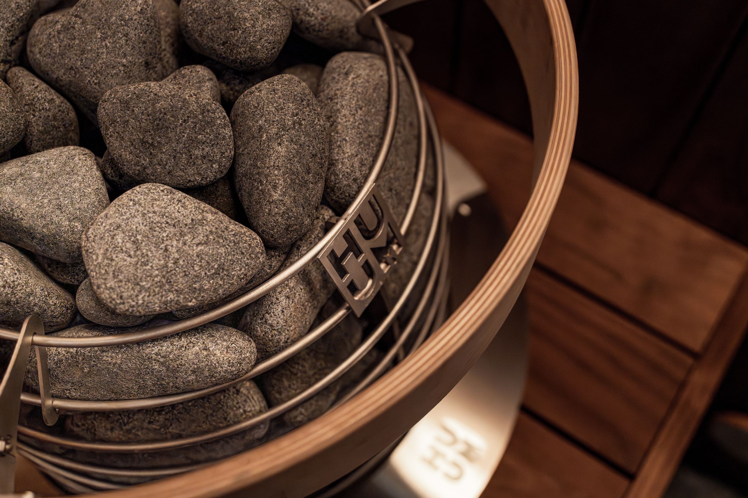 Close-up of a modern sauna heater filled with stones, showcasing Scandinavian design elements.
