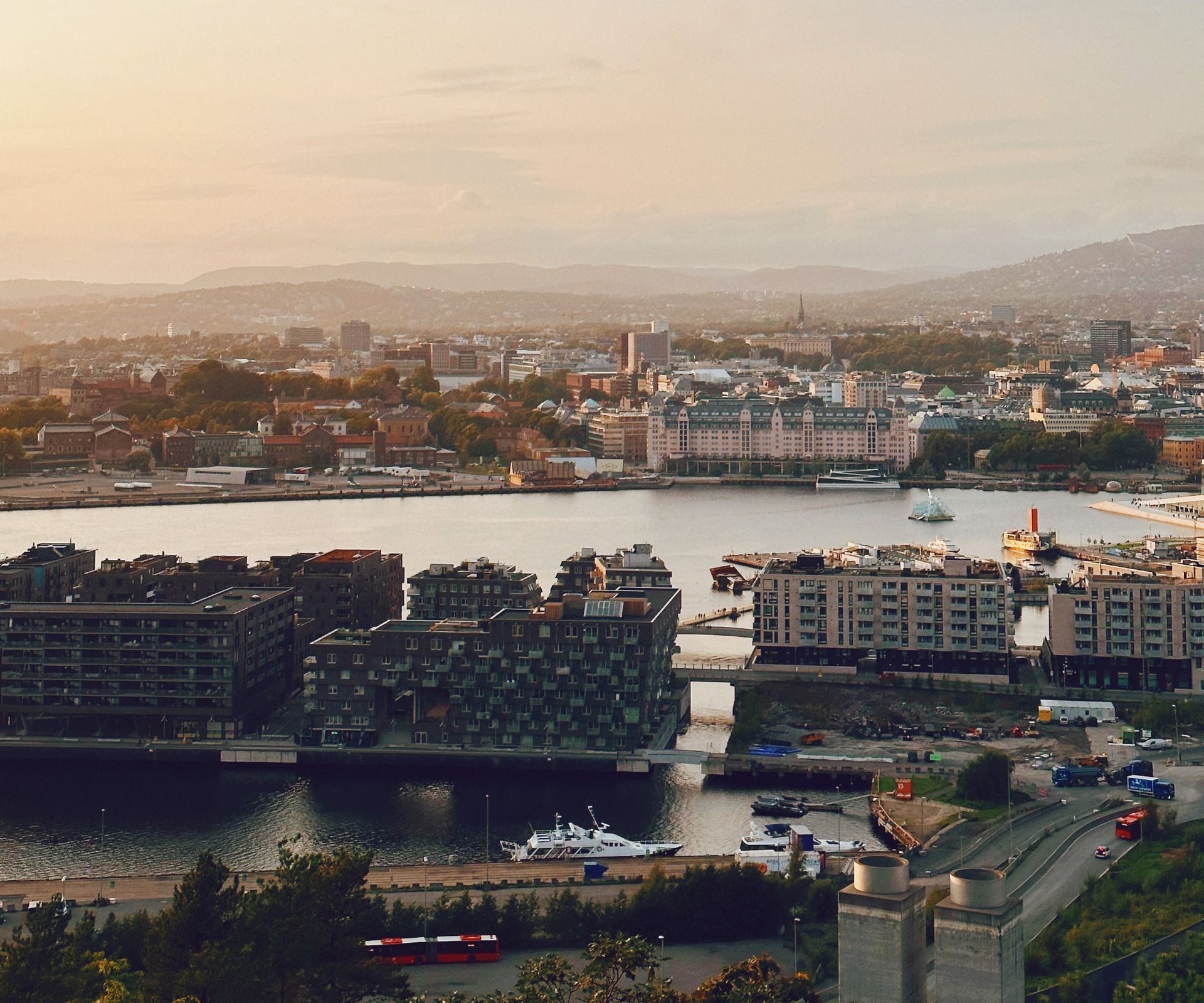 A breathtaking aerial view of Oslo's waterfront area at sunset, capturing the vibrant cityscape and serene fjord.