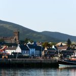 Beautiful coastal town of Dingle with fishing boat and church under hills.
