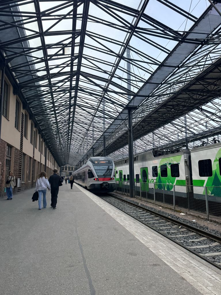 Helsinki Railway Station showcasing two modern trains under a glass canopy, bustling with passengers.